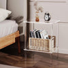 Modern clear acrylic side table used as a nightstand in a minimalist bedroom, with storage basket