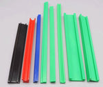 Assortment of CNC-cut plastic rods and square bars in black red and green colors showing material variety for custom fabrication projects