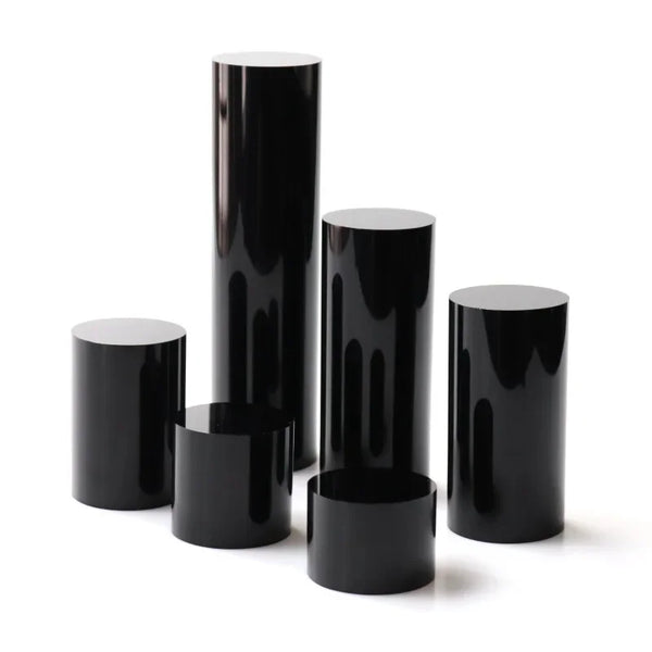 Multiple sizes of black acrylic cylinder stands arranged for size comparison