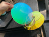 100mm iridescent acrylic circle showing rainbow dichroic color-changing effect in natural light